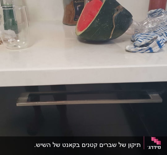 משטח שיש לבן מותקן במטבח על גבי ארונות כהים